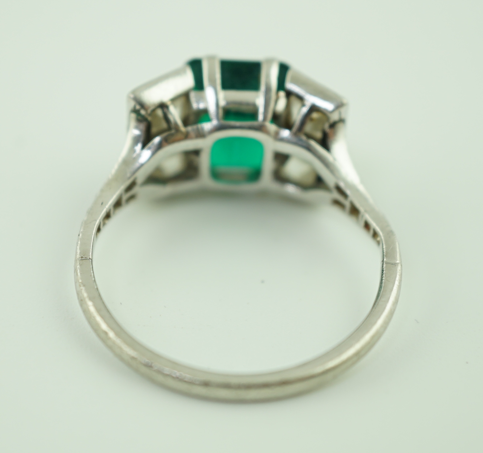 An Art Deco platinum, emerald and square cut diamond dress ring, with diamond chip set shoulders